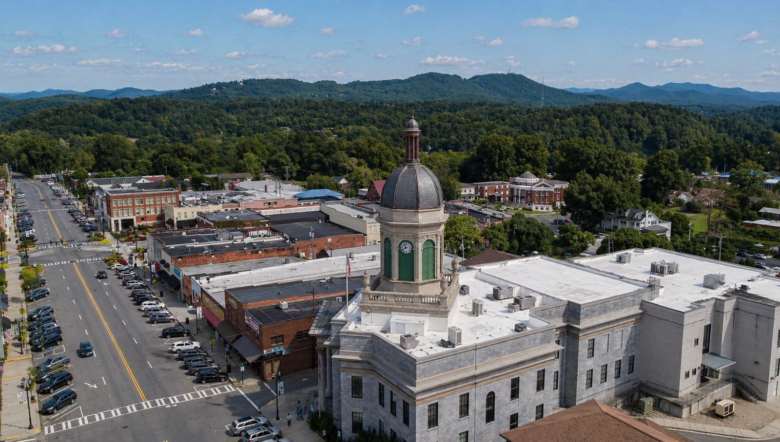 Aerial view of Murphy, NC downtown with historic buildings and lush green mountains in the backgroun.
