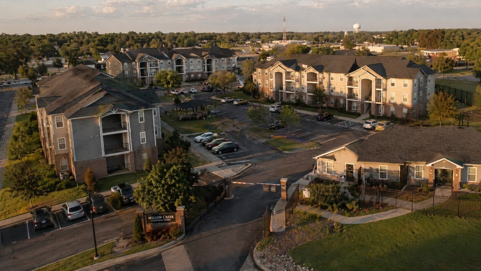 Aerial view of apartment complex with secure parking and well-maintained landscaping, highlighting s.