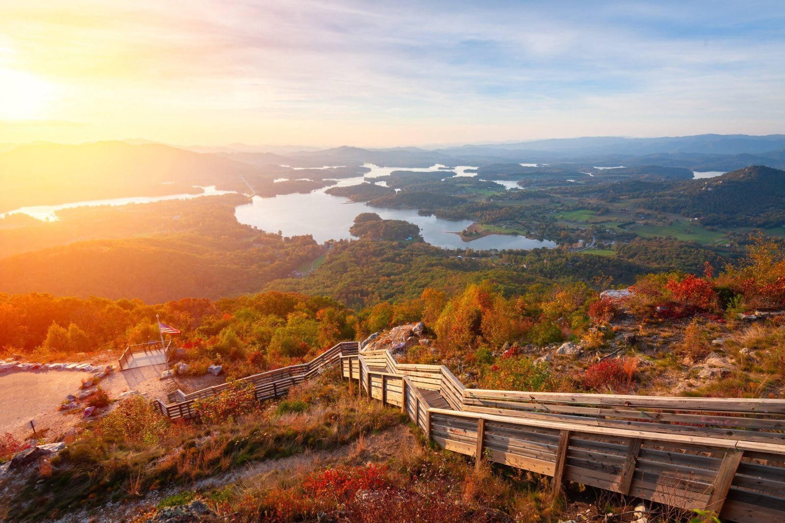 Scenic view of Hiawassee, GA with a wooden trail, colorful foliage, and a lake at sunset. Perfect fo.