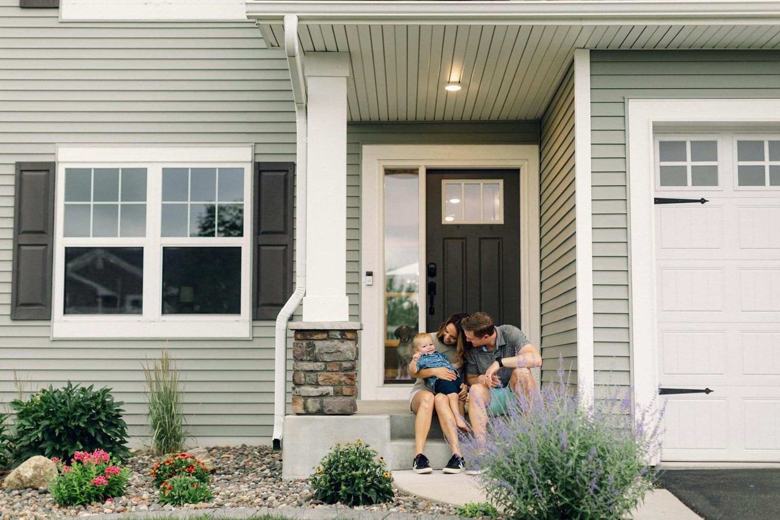 Family installing security system outside modern house for safety.