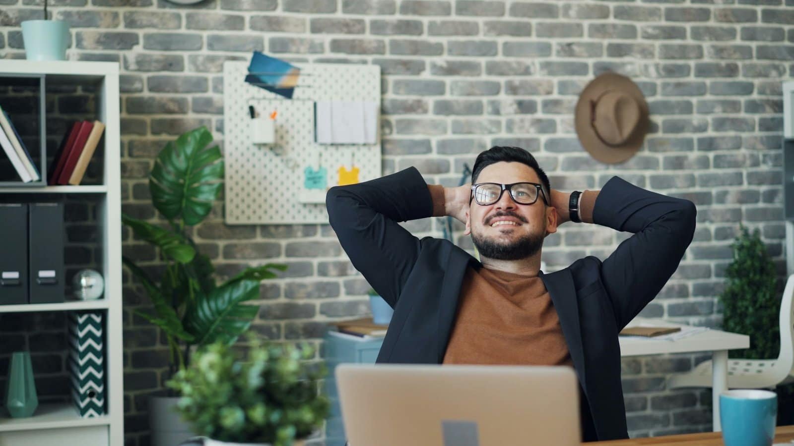 Happy man in office with laptop, promoting cybersecurity and secure coding.